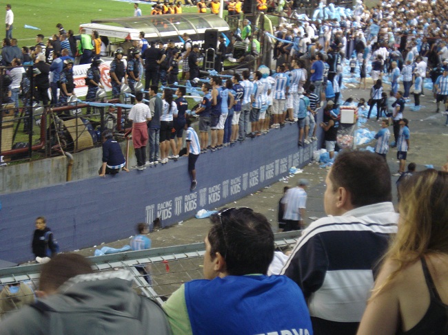 Torcedores sobre o muro que separa o campo da platéia acompanham a partida