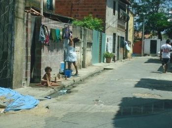 Criança na calçada ao lado de uma saída de esgoto