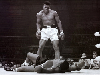 O segundo capítulo da rivalidade: na revanche, Ali derruba Liston, e cena é eternizada pelas câmeras fotográficas O segundo capítulo da rivalidade: na revanche, Ali derruba Liston, e cena é eternizada pelas câmeras fotográficas